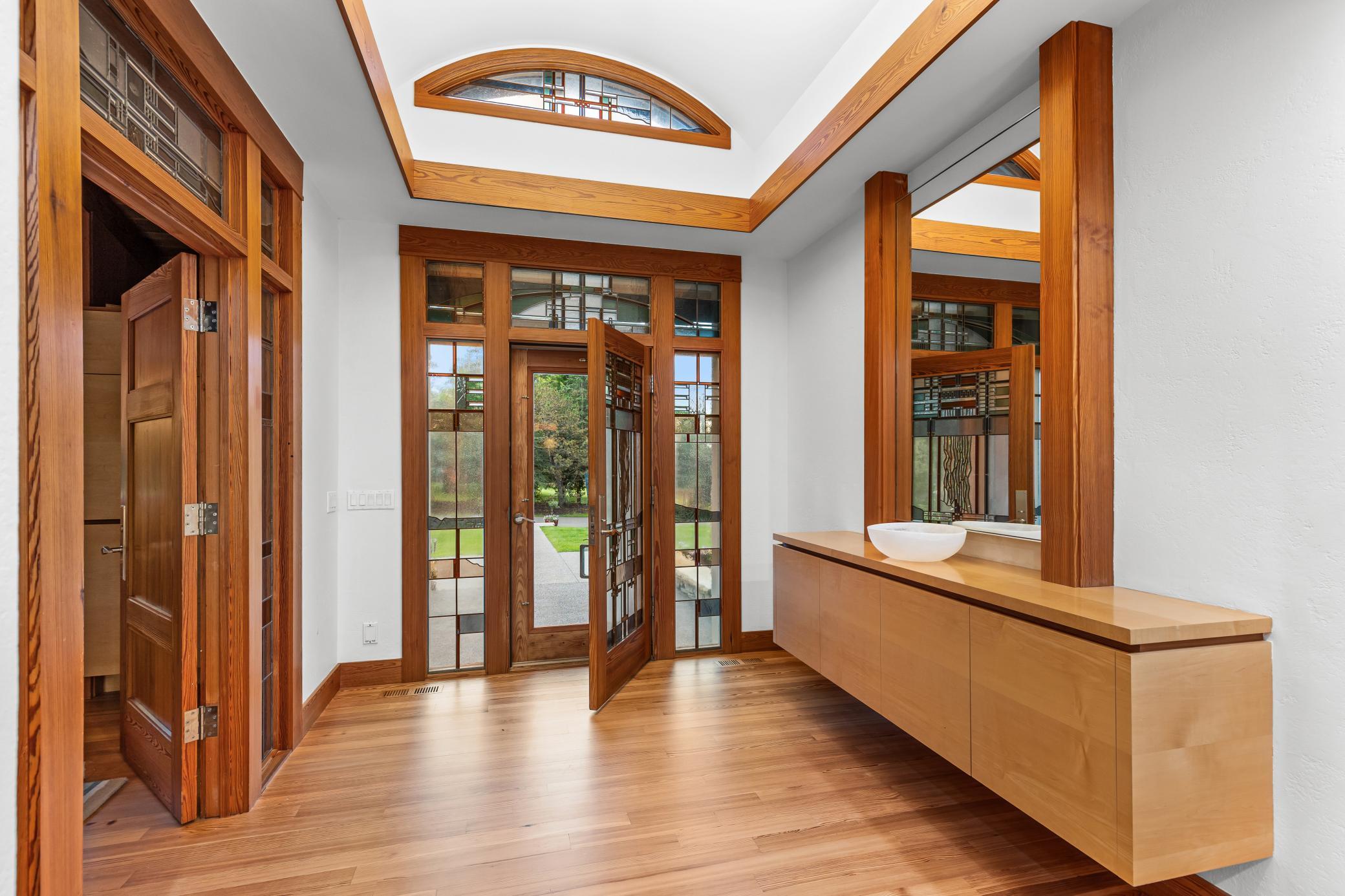 Welcome into the light filled foyer with stained glass accents and floating cabinetry