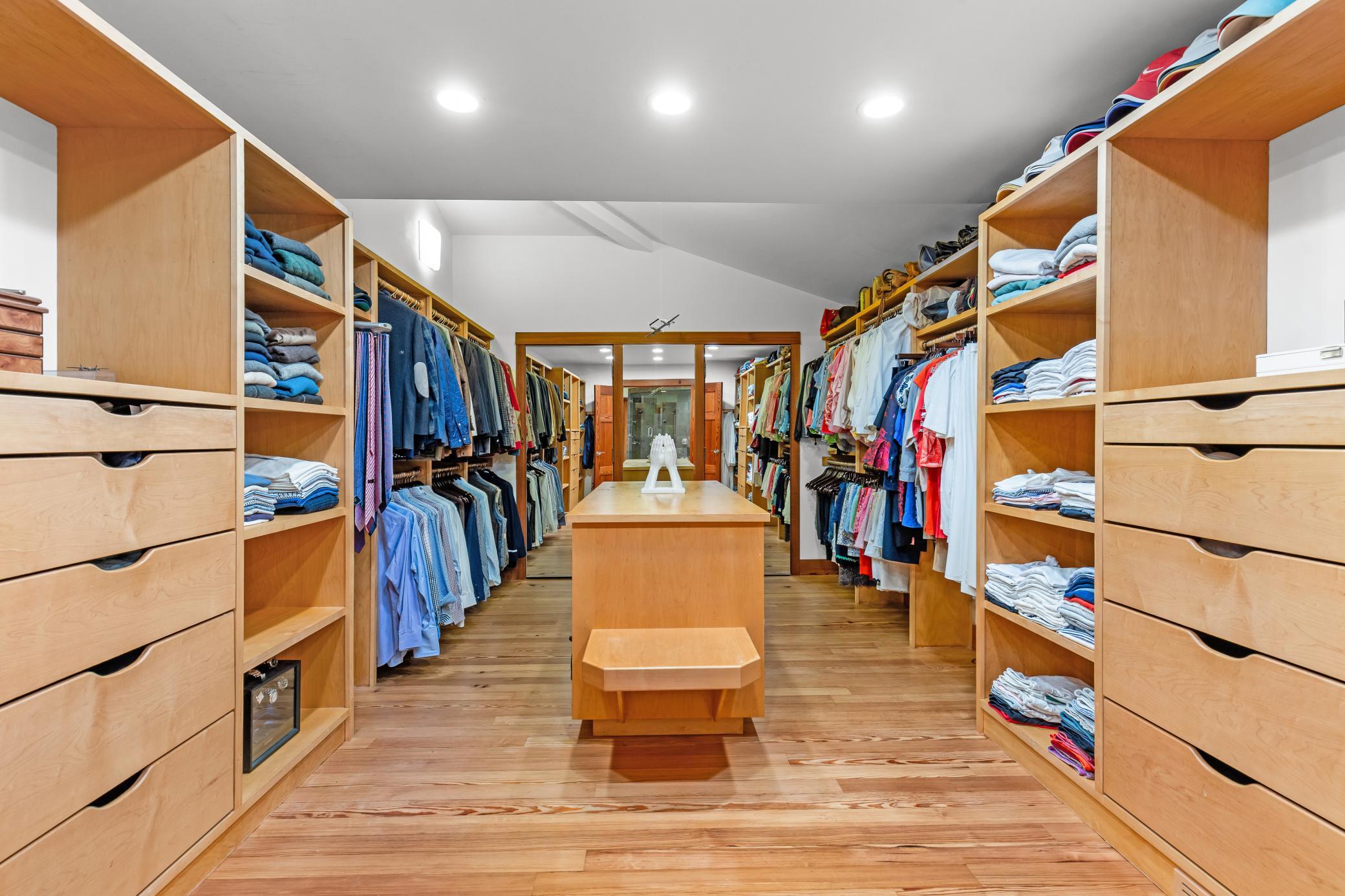 Primary bedroom closet with center storage and surrounding cabinetry