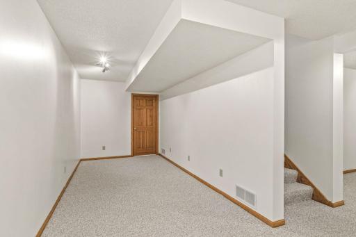 View of the opposite side of the lower level family room which leads to an unfinished storage/mechanical room.