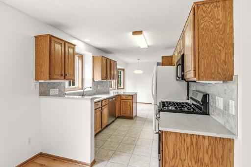 Updated kitchen with a window sink, abundant cabinetry, Corian counter tops and decorative tile backsplash to compliment.