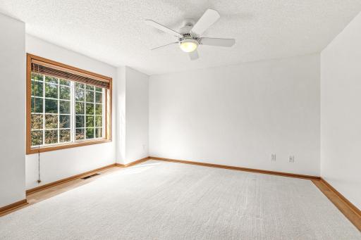 Grand sized bedroom #2 complete with a large window that overlooks the lush backyard, ceiling fan, large walk-in closet, and wood laminate flooring with a removable carpet.