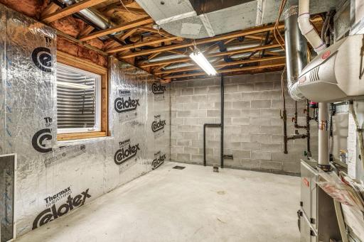 Second view of the unfinished mechanical/storage room showing the rough-in for a future bathroom and egress window.