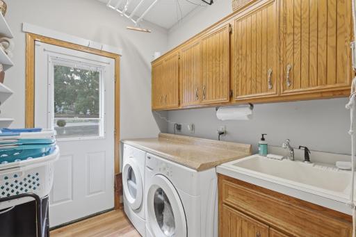 Main floor laundry with utility sink and cabinetry