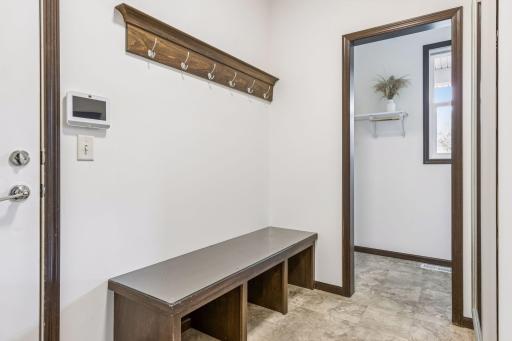 Mudroom with boot bench and adjacent walk-in storage closet.