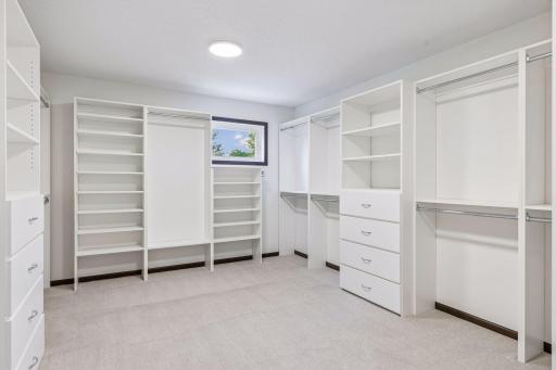 Primary walk-in closet with custom built-ins, freshly painted with new carpet.