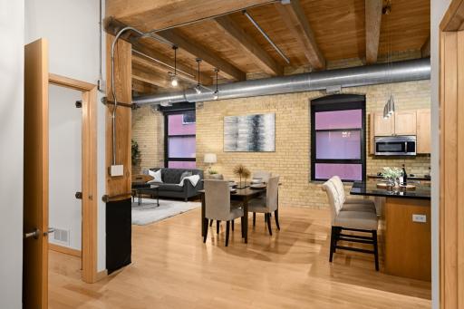 This corner residence features soaring ceilings, exposed brick walls, and timber beams