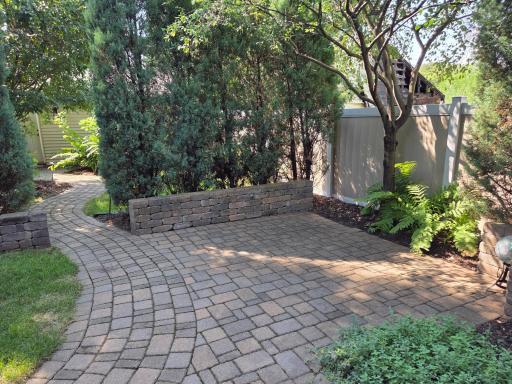 Relax on this patio with a wall & junipers separating it from the back part of the yard.