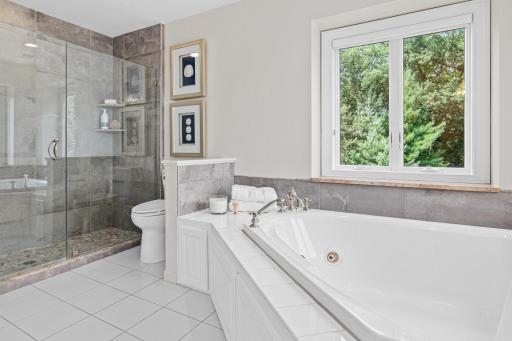 After a day enjoying Turtle Lake, retreat to the luxurious owner's bath featuring a relaxing tub, separate shower, and serene views designed for comfort and restoration.