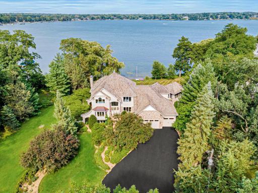 From above, the property's exceptional setting comes to life with sprawling lawns, mature trees, and expansive shoreline.