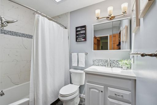 Full bath upstairs includes tile shower, updated vanity, and skylight.
