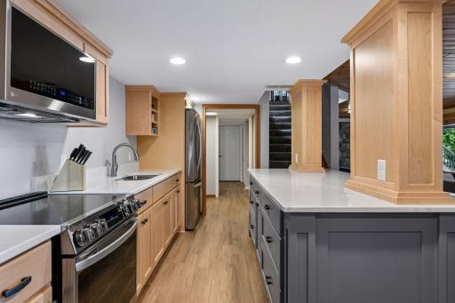 Updated lower level kitchen has custom cabinets, recessed lights, quartz counters, stove, microwave & stainless steel refrigerator.