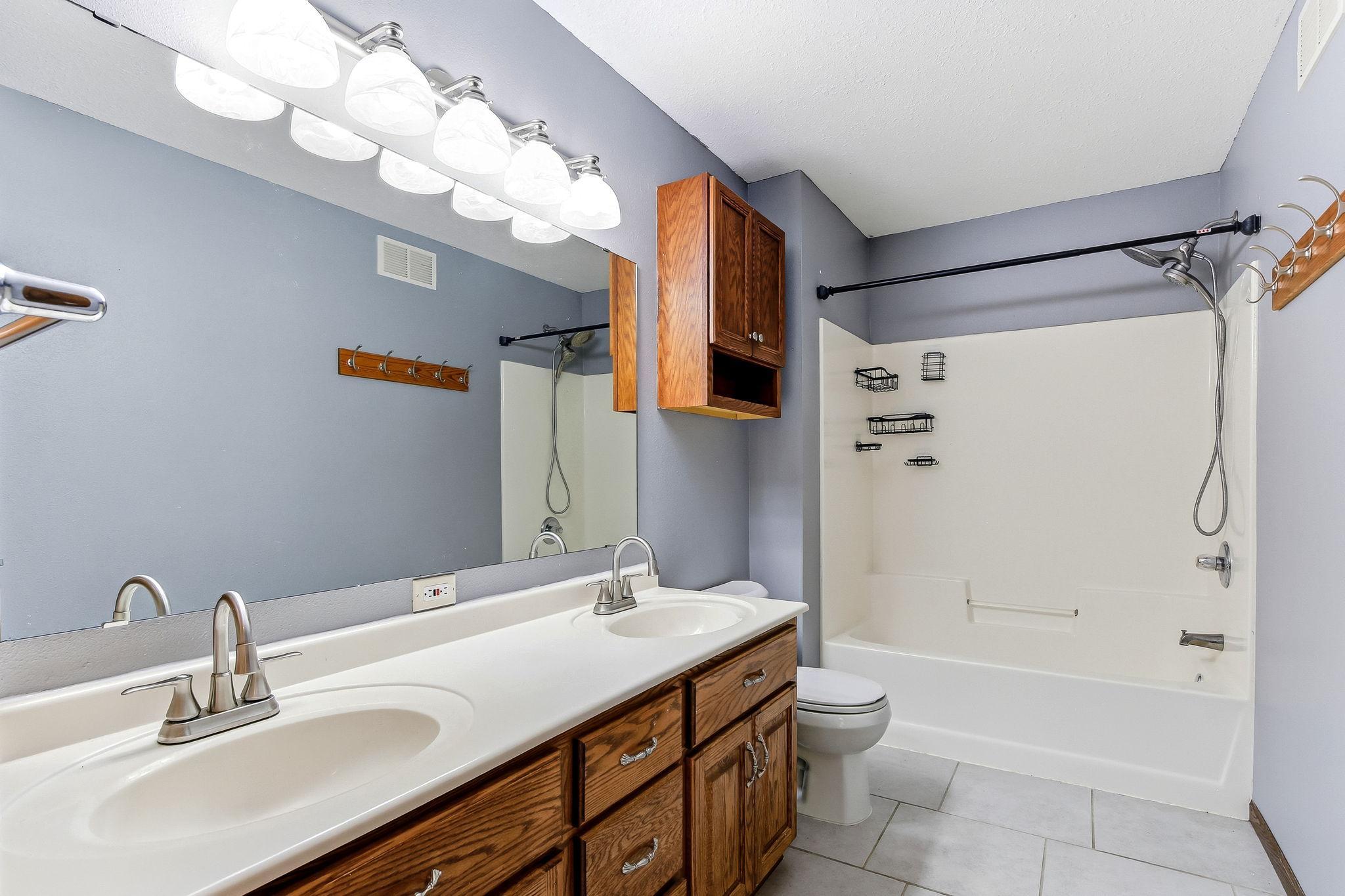 Copilot said: Spacious primary bath featuring a dual-sink vanity, abundant cabinetry, and generous storage. Tile flooring, ample counter space, and a large mirror create a functional and inviting space designed to accommodate busy daily routines.