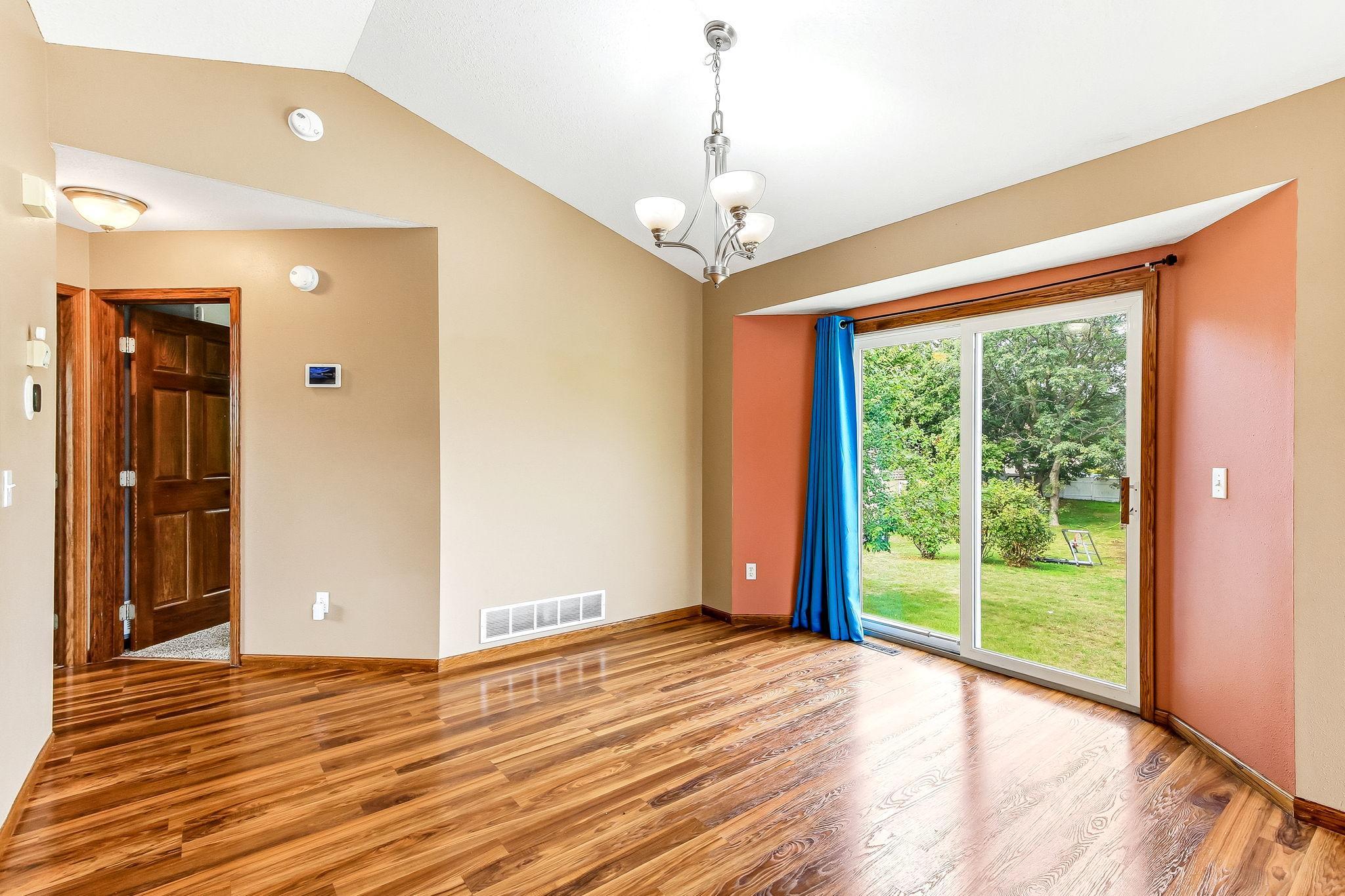 Bright and inviting dining area featuring vaulted ceiling lines, beautiful wood-look flooring, and a large sliding glass door that fills the space with natural light.