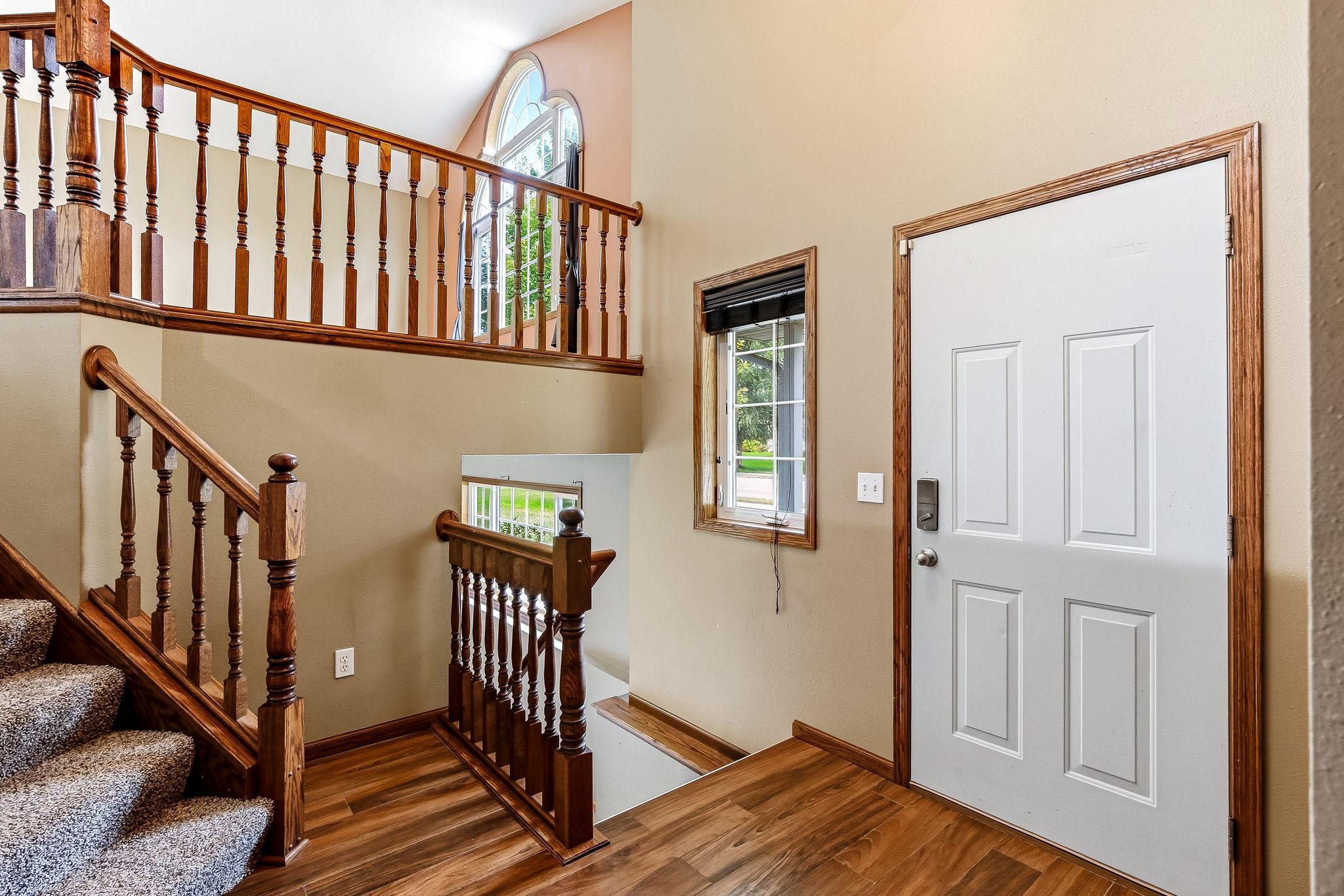 Inviting foyer with soaring ceilings, attractive wood tile flooring, and an open staircase that creates a bright, welcoming first impression. Natural light and open sightlines enhance the spacious feel as you enter he home.