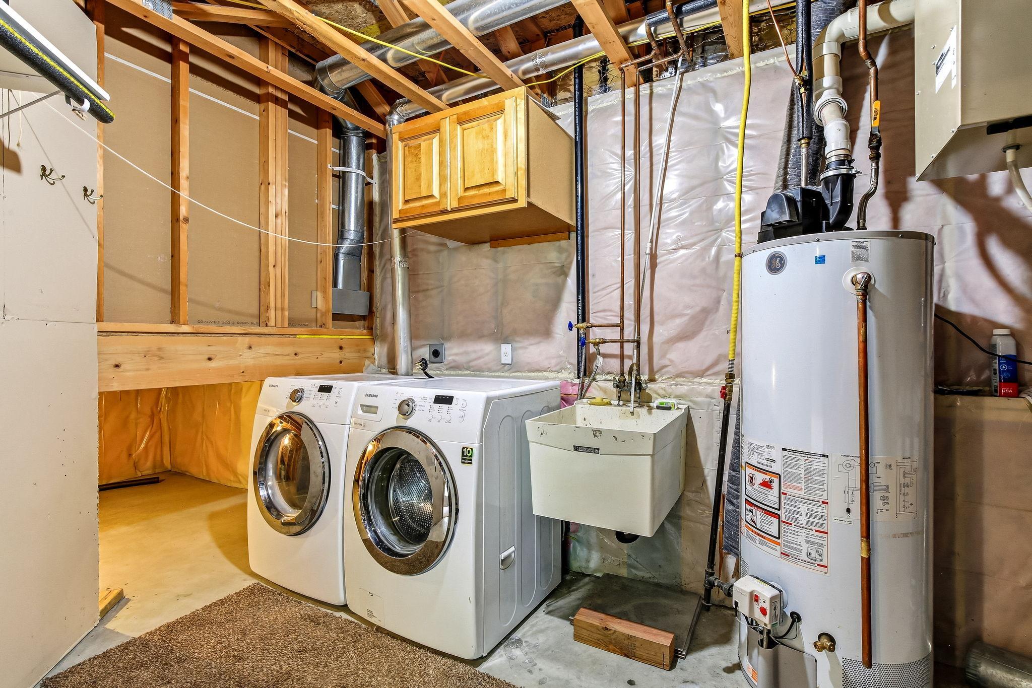 Nice utility area in basement with deep laundry sink and front load washer and dryer.