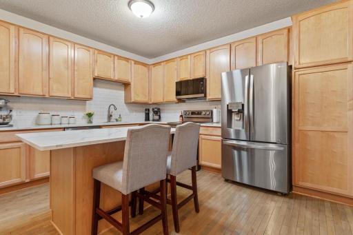 Maple cabinet with newer flooring, quartz counters and subway backsplash, a skylight and newer appliances