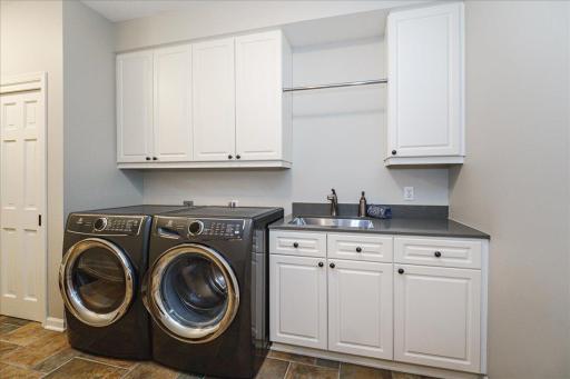 Main floor laundry with deep stainless sink and quartz counters