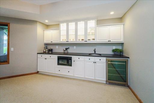 Large wet bar with beverage fridge, microwave, and honed granite countertops
