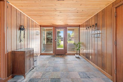 Beautiful three season porch that connects the garage to the home. The tile flooring and wood paneling create a warm and inviting space for morning coffee, a play area or an incredible mud room!