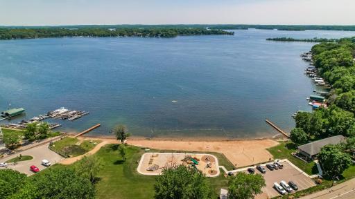 Expansive aerial view of Surfside Beach with swimming area, playground, and panoramic Lake Minnetonka vistas.