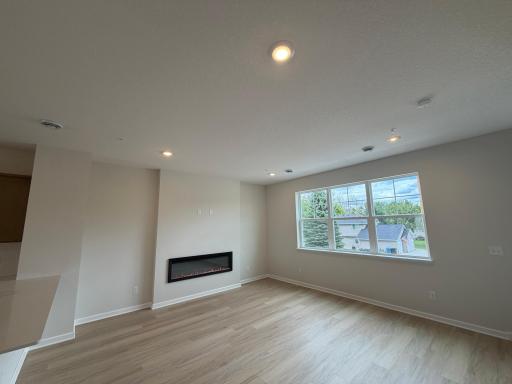 This spacious living room has excellent scenery featuring large windows, a fireplace, and enough space for even the biggest couches.