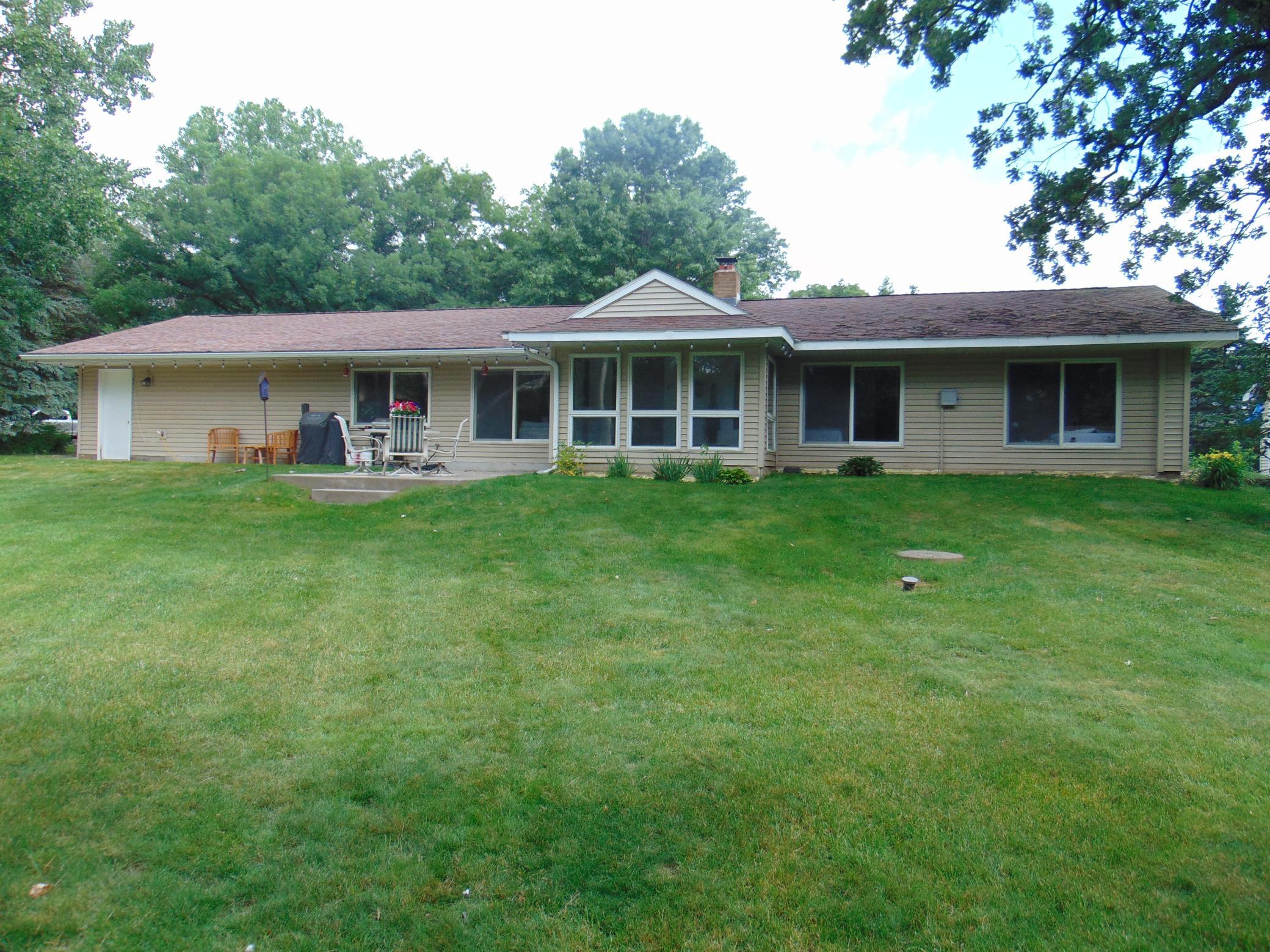 Front of home with views of landscaped yard and woods.