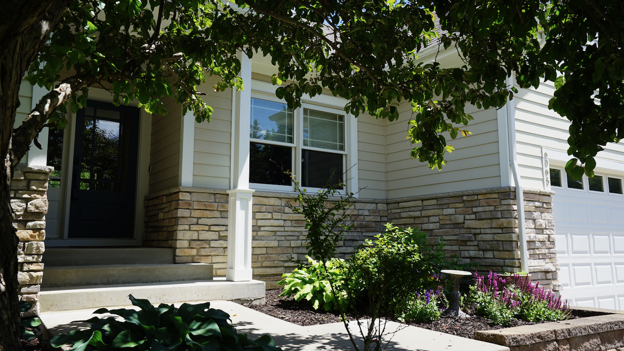 Custom stone walls and terraced perennial gardens define the approach, creating a natural transition to the front entry.
