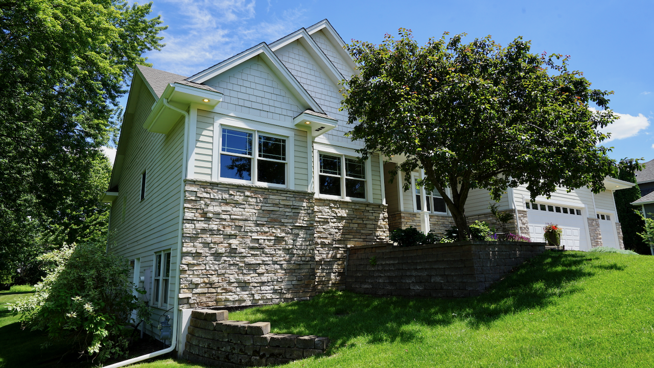Lovely landscaping, beautiful terraces, and a view of the side entrance to the lower level.