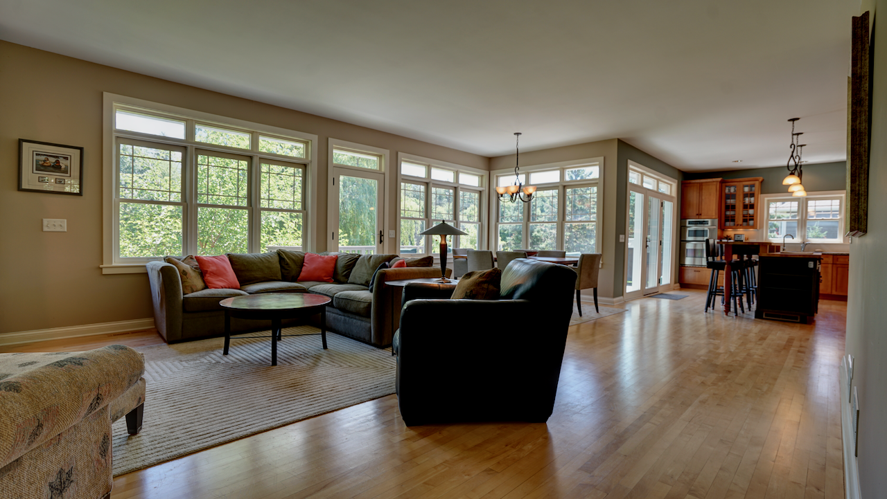 Recessed lighting and wide windows bathe the living space in light, highlighting the premium maple hardwood floors.