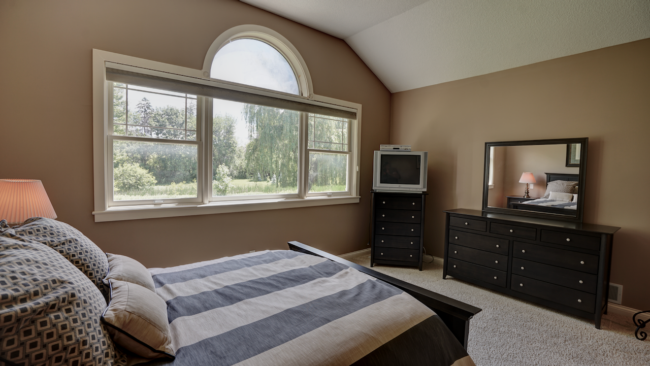 A massive picture window serves as living art, framing a serene, uninterrupted view of the private, heavily wooded backyard. A true retreat, elevated by elegant vaulted architectural ceilings that expand the sense of space.
