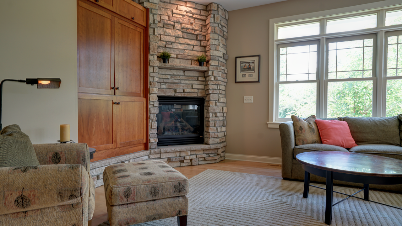 The 18x16 main living room is anchored by a dramatic floor-to-ceiling stone gas fireplace and original solid cherry woodwork.