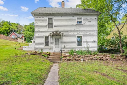 A stone-lined garden bed and gently rolling backyard offer a peaceful, green escape just steps from the home's rear entrance full of potential for outdoor living.
