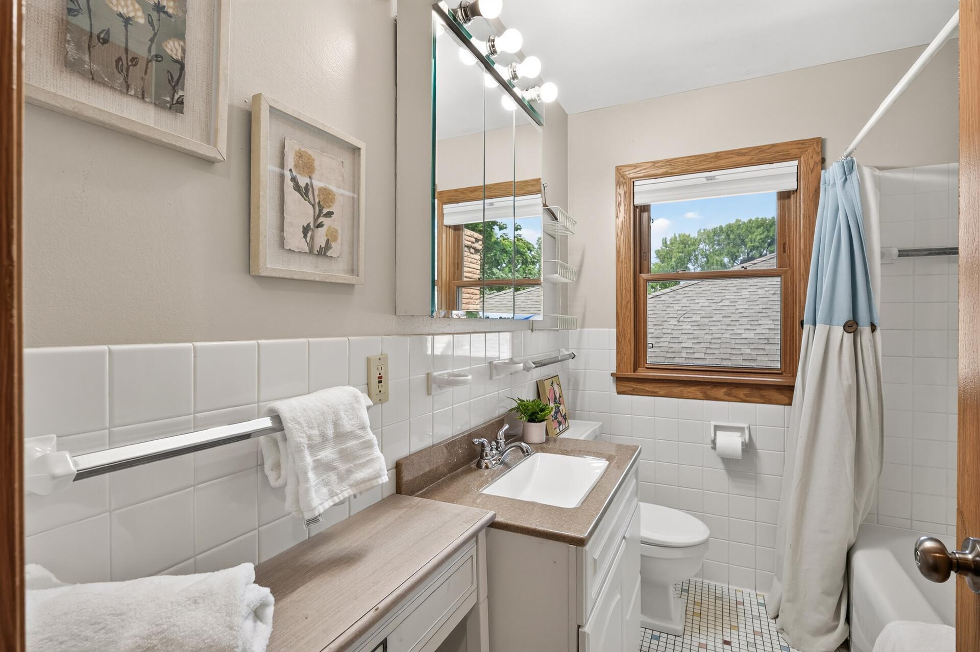 A full main-level bathroom offers timeless finishes and everyday convenience.