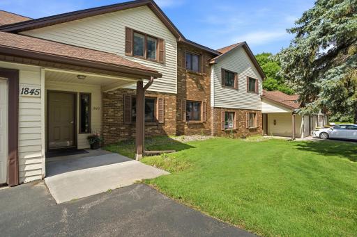 Exterior view highlighting the covered entrance, brick and siding exterior, and front lawn.