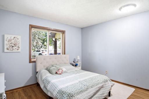 Secondary bedroom with large window, wood-look flooring, and neutral finishes