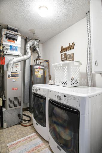Dedicated laundry and utility room with full-size washer and dryer, additional storage cabinetry, and mechanical systems conveniently located together.