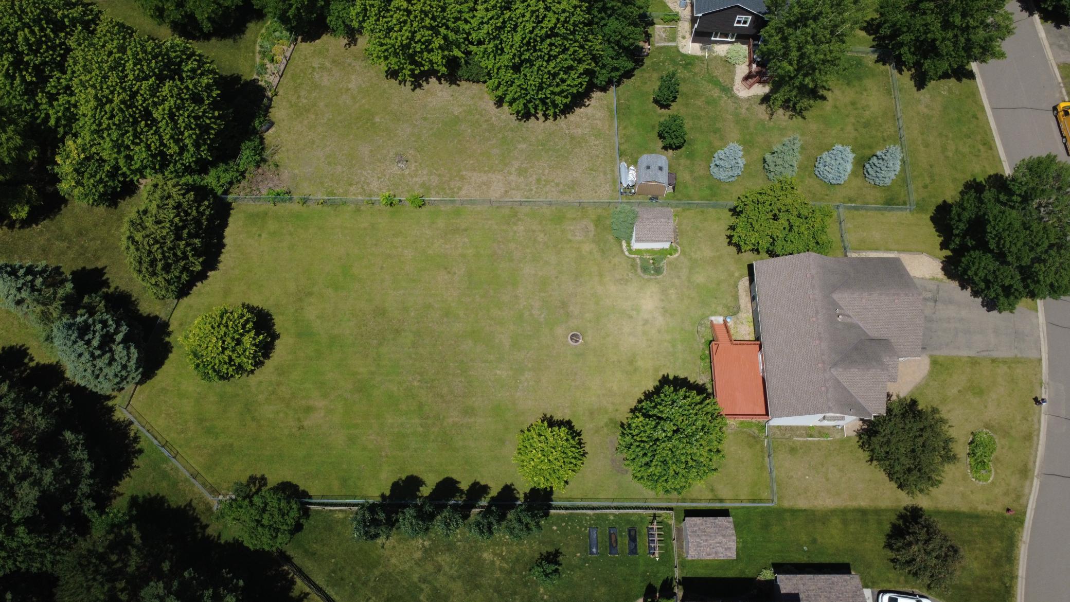 Aerial of giant fenced in backyard including storage shed.