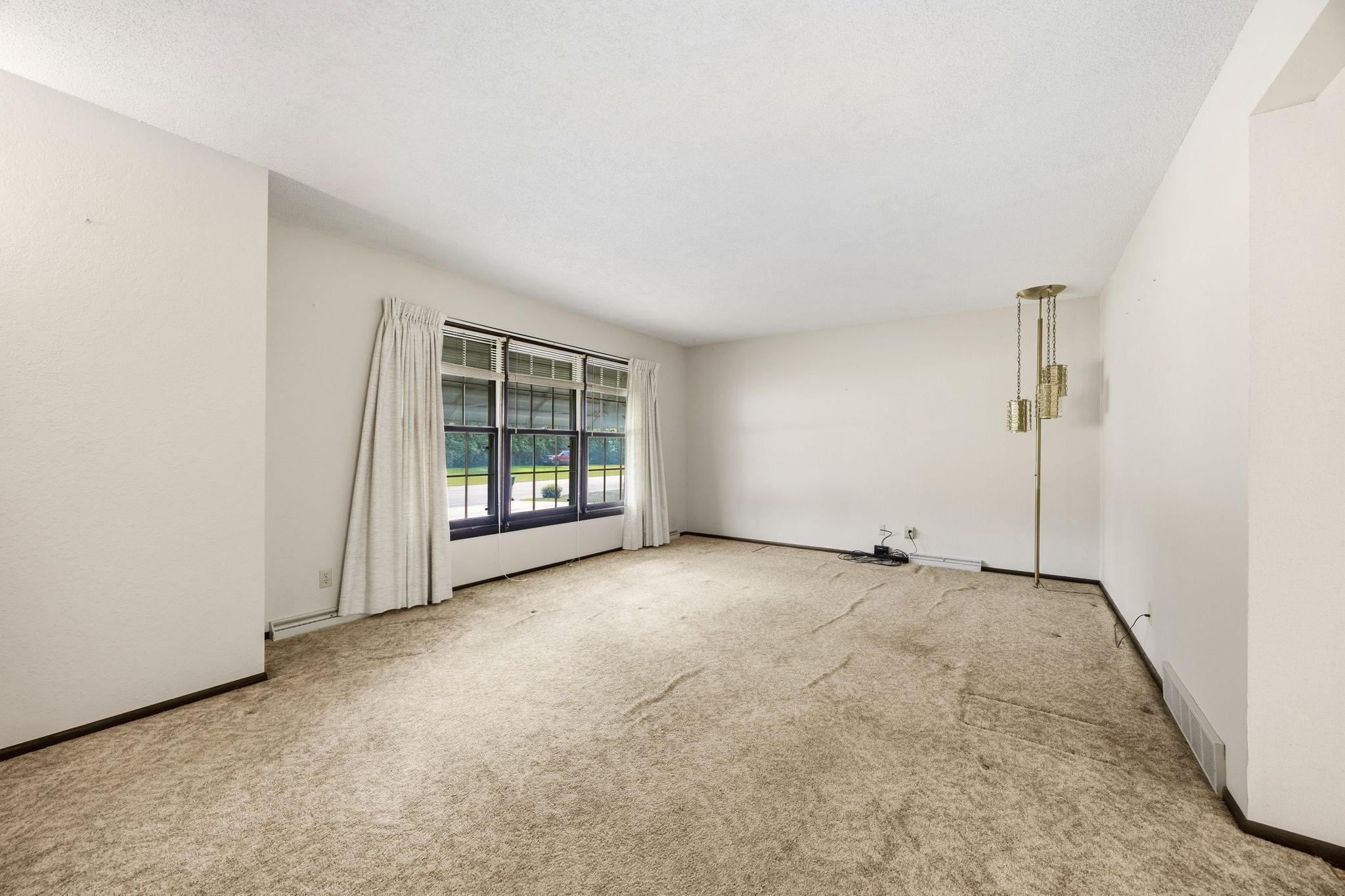 Spacious living room with oversized windows that fill the space with natural light, creating a warm and inviting atmosphere.