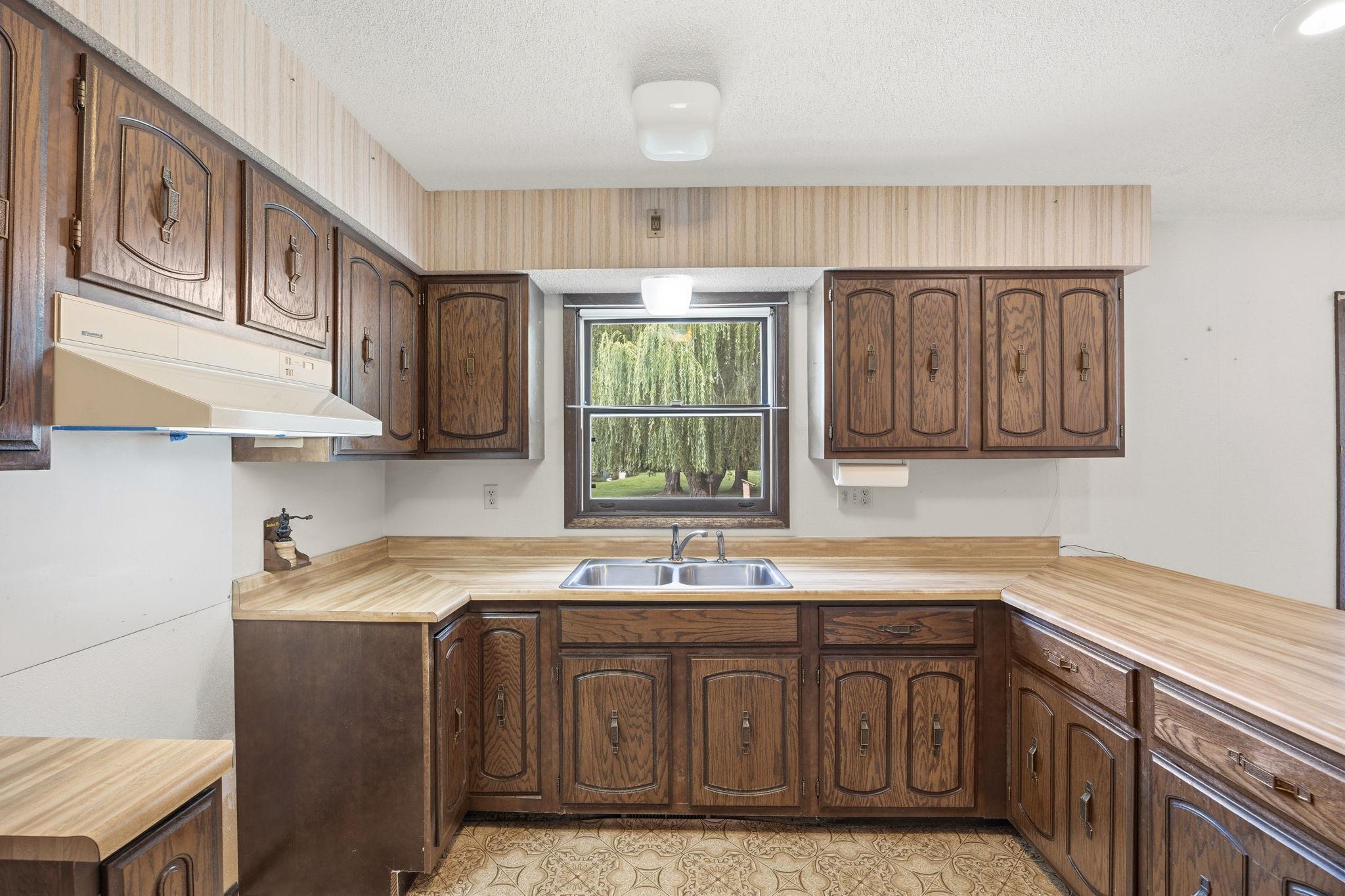 Spacious kitchen with abundant cabinetry, expansive counter space, and a window overlooking the beautiful backyard.