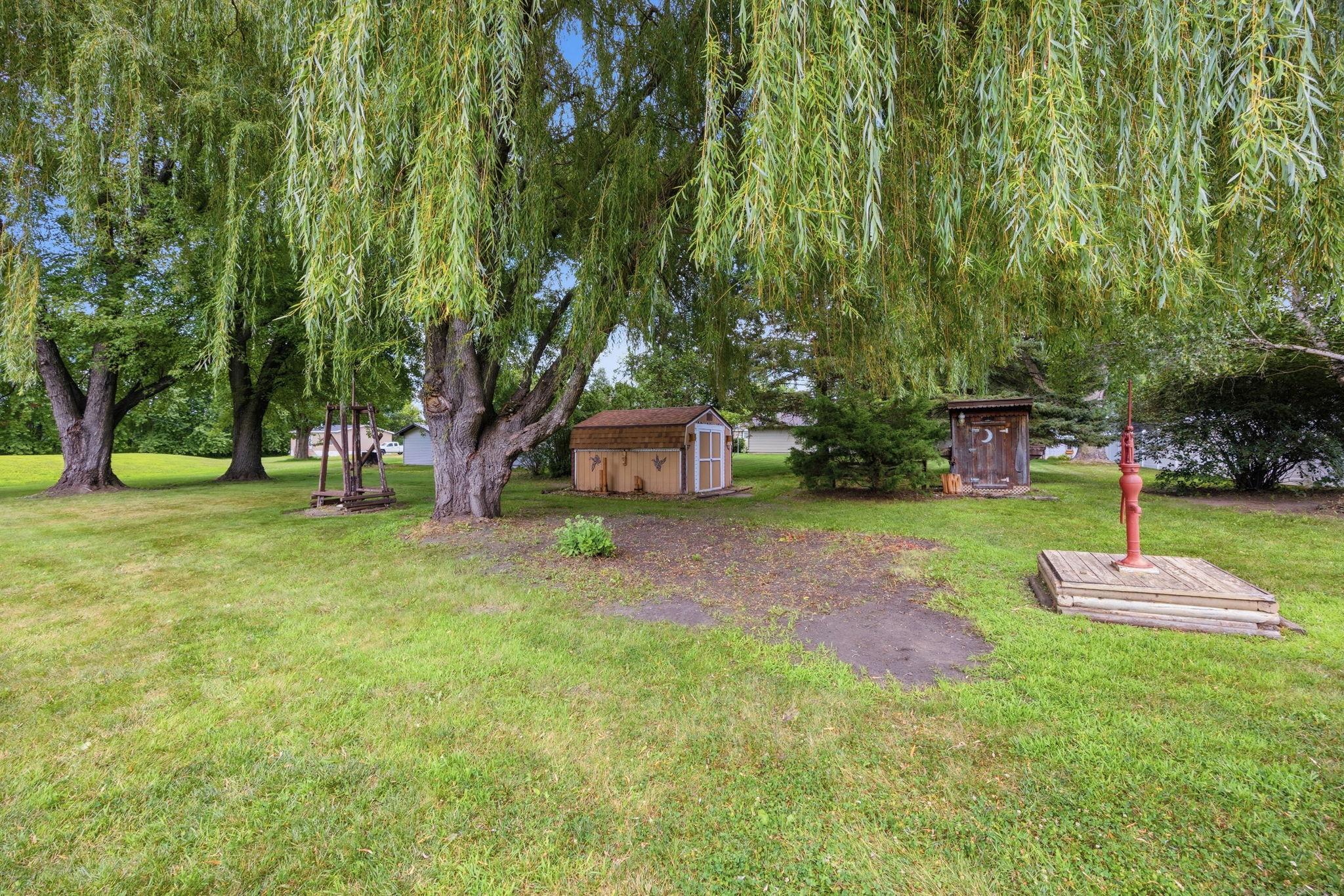 Mature willow trees create a peaceful backyard retreat complete with storage sheds and plenty of room to enjoy the outdoors.