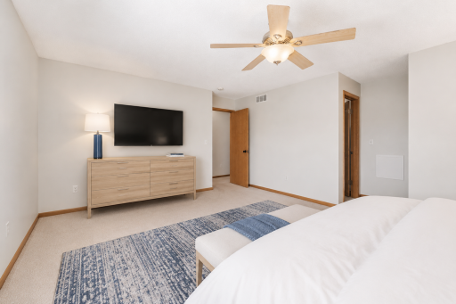 Primary bedroom with ceiling fan, generous wall space, and direct access to private full bathroom. (virtually staged to show potential).png