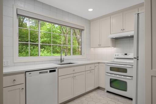 A remodeled bright white kitchen with ambient heated floors and a huge window to the backyard