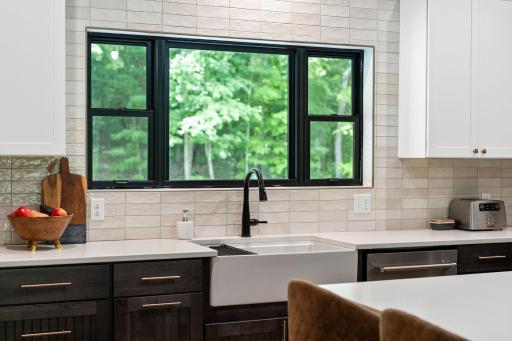 Farmhouse sink, black windows, black finishes and a private view