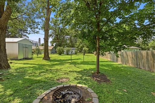 Fire pit and another view of the large lot and trees in the backyard.