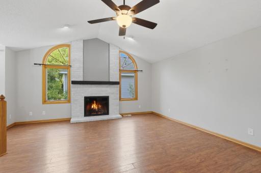 Virtual fire, Another angle of the spacious living room highlighting the open layout, vaulted architecture, and the central fireplace. Large windows showcase views of the surrounding greenery.
