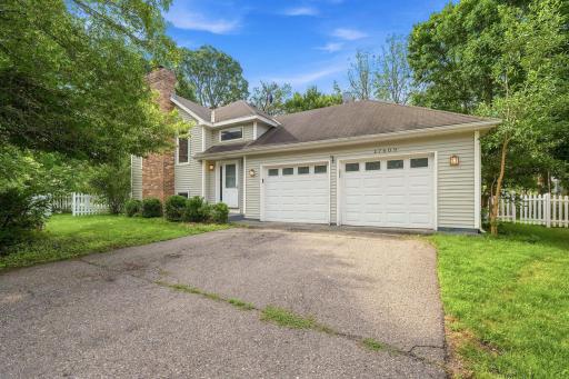 Exterior view of the charming single-family home featuring an attached two-car garage, a concrete driveway, and mature trees providing excellent curb appeal.