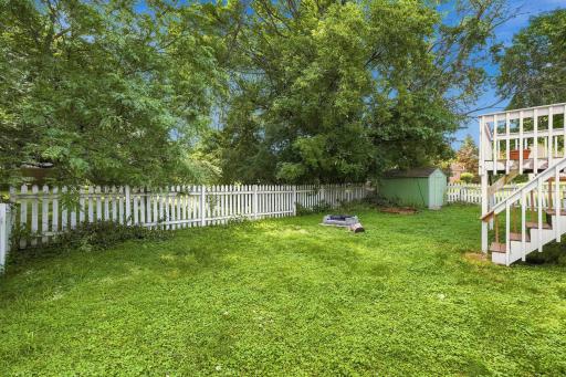 Expansive, flat green backyard bordered by a white picket fence, providing a secure and open outdoor space for recreation or pets.