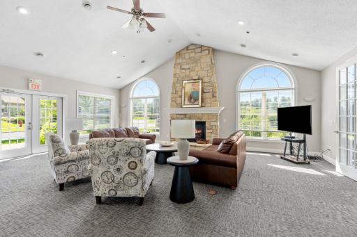 Elegant clubhouse lounge area anchored by a stately floor-to-ceiling stone fireplace accent wall and cozy conversational seating!