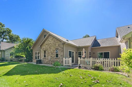 Beautiful rear & side elevations, showcasing classic stone masonry accents, dual patio slider doors, and a private, fenced-in concrete seating area!