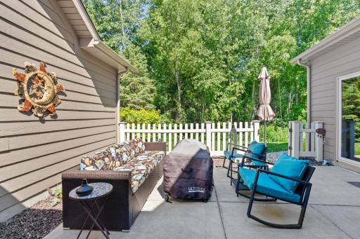 Private concrete back patio offering total outdoor serenity and a beautiful seasonal view, backing up directly into a peaceful, mature tree-line along the Crow River basin!